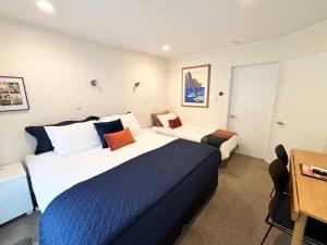 a hotel room with two beds and a desk at Studio Stay Narrow Neck Beach in Auckland