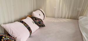a bed with four pillows on it in a room at 6 Engo Cottage - Benanda Forest Resort in Masaka