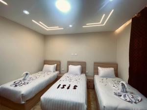 two beds in a room with two swans on them at Isis Pyramids View Inn in Cairo