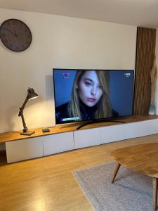 einen großen Flachbild-TV im Wohnzimmer mit einer Uhr in der Unterkunft Maison bien-être avec bain nordique et sauna in Ferrières + 19 Fotos