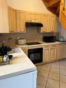 eine Küche mit Holzschränken und einem Herd mit Backofen in der Unterkunft Maison bien-être avec bain nordique et sauna in Ferrières