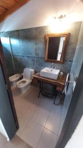 ein Badezimmer mit Waschbecken, Toilette und Spiegel in der Unterkunft Casa Amsterdam in Villa Carlos Paz