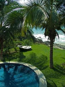 a swimming pool next to a palm tree and a boat at Casa Mar Beachfront Jungle Villa in Palapa Ganesh in Sayulita