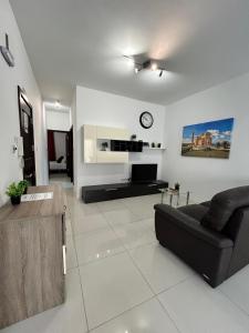 a living room with a couch and a clock on the wall at TJS Apartments 2 in Il-Gżira