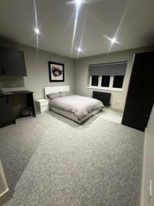 a bedroom with a bed and a desk and two windows at Abbey House in Waltham Abbey