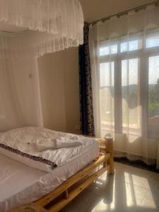 a bed sitting in a room with a window at 5 Empologoma Cottage - Benanda Forest Resort in Masaka