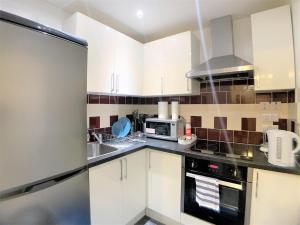 a kitchen with white cabinets and a sink and a microwave at Cosy Rooms next to St Pancras Station in London