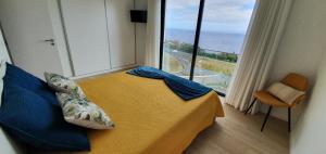 a bedroom with a bed and a large window at Sea&Sunrise Village in Caniço