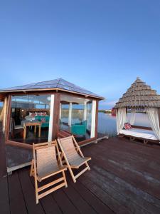 a wooden deck with two chairs and a gazebo at Titicaca Magical Lodge Peru in Puno