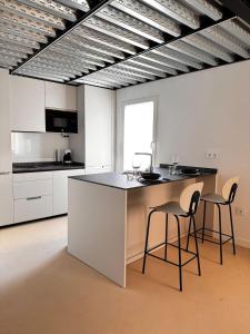 a kitchen with white cabinets and a island with two chairs at VUT La Casa de la Vega in El Barraco +25 photos