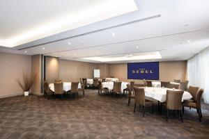 un restaurant avec des tables et des chaises et un panneau indiquant la recherche dans l'établissement The Sebel Melbourne Kew, à Melbourne