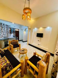 a living room with a couch and a table and a tv at 2 Envubu Cottage - Benanda Forest Resort in Masaka