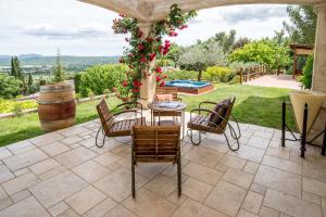een patio met een tafel en stoelen en een vat bij Les chambres du Restaurant le Castellaras - Teritoria in Fayence
