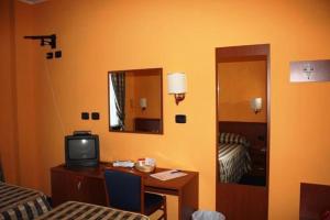 CantalupaにあるHotel Tre Dentiのデスク、テレビ、鏡が備わる客室です。