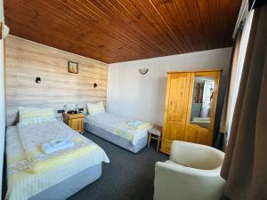a room with two beds and a chair in it at Къща за гости Даутев Връх in Bansko