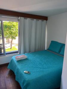 a bedroom with a blue bed with a window at Apartamento em Vilas do Atlântico in Lauro de Freitas