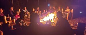 a group of people sitting around a fire at 2 Envubu Cottage - Benanda Forest Resort in Masaka