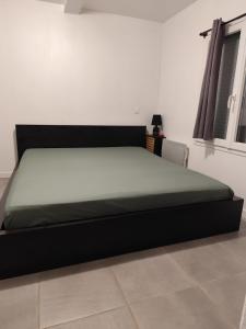 łóżko z czarną ramą w pokoju w obiekcie Bienvenue à Naudebal w mieście Rebourguil