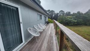 three white chairs sitting on a wooden deck at Countryside Retreat- DS Holiday Home in Carngham