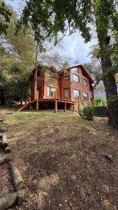 une grande maison sur un champ avec un arbre dans l'établissement Vine para Quedarme, à San Martín de los Andes