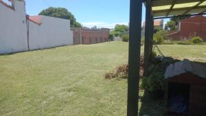 a yard with grass and a fence and a building at Casa pali in Miramar