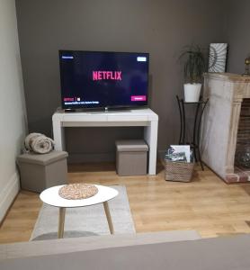 ein Wohnzimmer mit Fernseher und Tisch in der Unterkunft Gîte Val de Saône et Beaujolais, Clos Beaudet in Saint-Didier-sur-Chalaronne