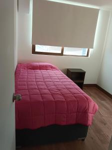 a bedroom with a pink bed and a window at Acogedor Dpto en LLanquihue in Llanquihue +4 photos