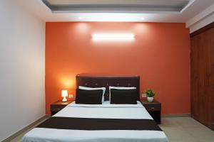 Un dormitorio con una cama con una pared naranja. en Hotel O Noida Stays, en Indirapuram