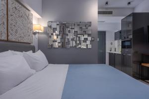 a bedroom with a large white bed and a kitchen at Square Elegant Suites in Thessaloniki