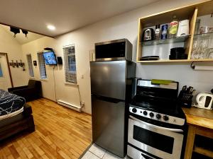 Una cocina con refrigerador de acero inoxidable y estufa. en Cozy Cabin Centrally Located Close To Walking Trails And Beaches!, en Ucluelet