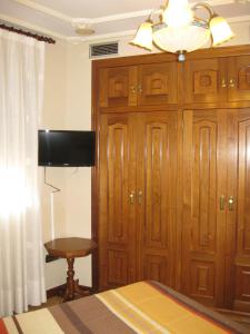 1 dormitorio con un gran armario de madera y TV en Hostal Granada, en Salamanca