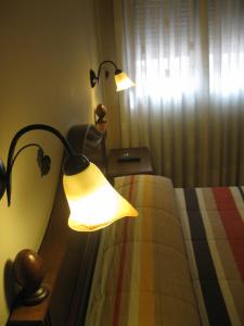 een slaapkamer met 2 lampen op een bed en een raam bij Hostal Granada in Salamanca