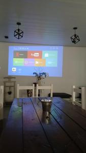 a large projection screen in a room with a wooden table at Quinta Las Flores by Ginkgo Hostel in La Plata