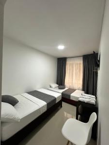 a room with two beds and a chair in it at LA CASONA Finca Hostal in Apía