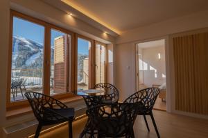 a dining room with a table and chairs and windows at Bjelasnica Mountain Retreat in Bjelašnica