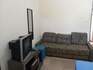 a living room with a couch and a tv at Casa completa Estância Turística de Ribeirão Pires in Ribeirão Pires +1 photo