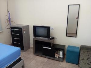 a bedroom with a tv and a bed and a mirror at Casa completa Estância Turística de Ribeirão Pires in Ribeirão Pires