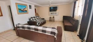 un salon avec deux chaises et un canapé dans l'établissement casa do fred enseada, à Guarujá