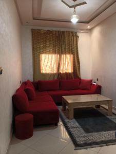 Una sala de estar con un sofá rojo y una mesa de café. en Abdelwahab EL KHAYATI, en Zemmour Touirza