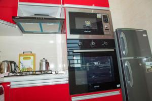 a red kitchen with a stove and a microwave at Résidence FARASELAA in Dakar
