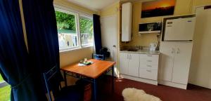 a small kitchen with a table and a refrigerator at Waikanae Accommodation Studio B&B in Waikanae