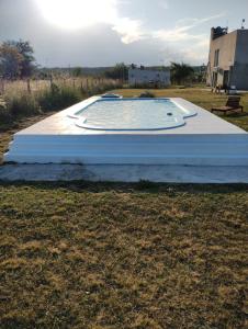 een zwembad in een veld met de zon op de achtergrond bij Cabañas MoonRose in Concepción del Uruguay