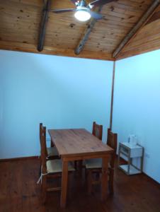 een eetkamer met een houten tafel en een plafondventilator bij Cabañas MoonRose in Concepción del Uruguay