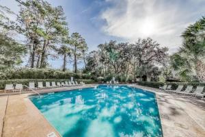 a swimming pool with chairs and trees at Rare Large 3 BR Near Beach Shops Restaurants & Bars Huge Pool & Free Tennis in Hilton Head Island