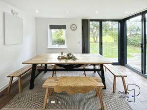 a dining room with a wooden table and benches at Hên Stablau - Spacious Pet-Friendly Welsh Retreat by PolkaStays in Llanfihangel-Glyn-Myfyr