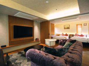 a hotel room with a couch and a flat screen tv at The GOAT AWAJI in Kusumoto