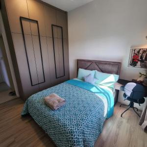 a bedroom with a bed with a blue blanket and a desk at LoveStayBangi - Studio, Sunway Gandaria, Bangi in Bandar Baru Bangi +1 photo