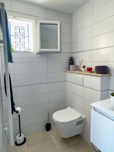 a white bathroom with a toilet and a window at Le Nid'Isle - Stationnement privé gratuit - Wi-Fi performant - Climatisation in LʼIsle-sur-la-Sorgue