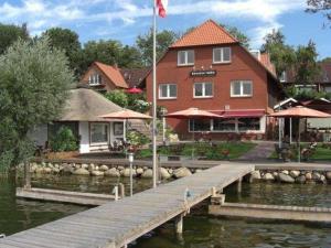 a dock in front of a building with a house at Hotel am See Römnitzer Mühle in Römnitz