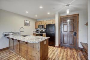 a kitchen with wooden cabinets and a black refrigerator at Cozy Ski Chalet with Large Balcony condo in Breckenridge